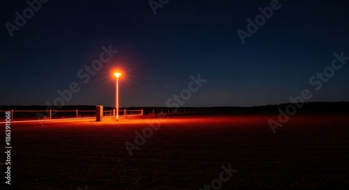 A solitary street lamp illuminates a dark rural landscape at night under a starry sky.