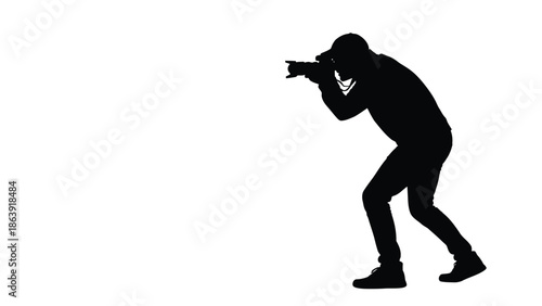 Silhouette of a male photographer crouching down while taking a picture with a professional camera