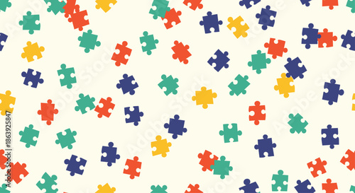Colorful jigsaw puzzle pieces in red, yellow, blue, and green are scattered randomly over a light cream background to form a playful pattern.