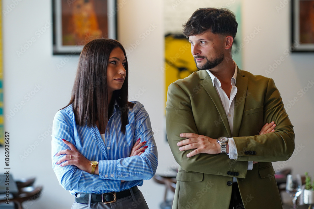 Obraz premium Two people standing with crossed arms in a modern indoor setting during the day
