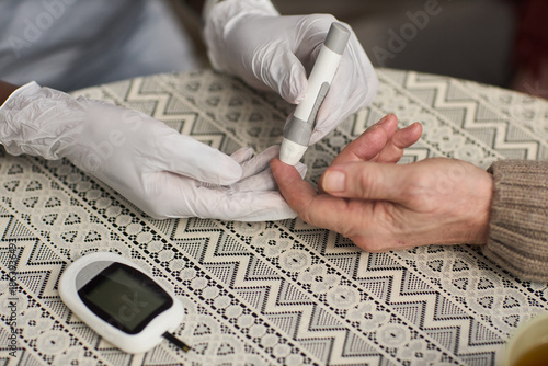 Wallpaper Mural Caucasian senior hand receiving blood glucose test from gloved healthcare worker, medical device and glucometer visible on patterned tablecloth, monitoring diabetes management Torontodigital.ca