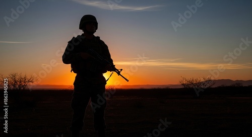 A silhouetted soldier stands alert during a desert sunset, holding a rifle