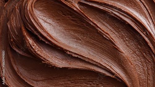 Macro texture of smooth dark chocolate frosting with creamy swirls