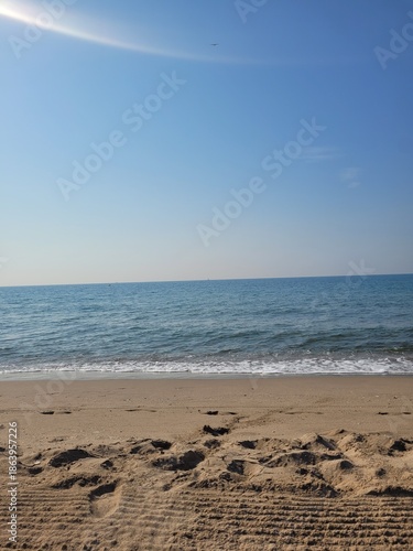 Serene deserted beach, empty sandy shore, calm waves, tranquil tropical landscape, peaceful ocean scene, relaxing summer getaway.
