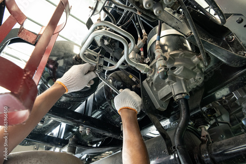 Konstfotografi Mechanic hands inspecting and repairing the chassis and undercarriage of a heavy truck 
Close-up of a professional technician in uniform working under a vehicle