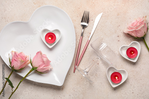 Beautiful table setting for Valentine's Day with candles and rose flowers on beige grunge background