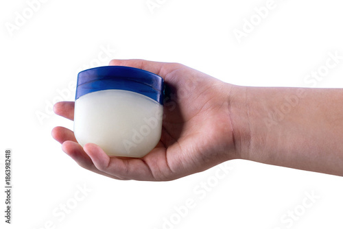 Hand holding a small jar of petroleum jelly, isolated on a black background