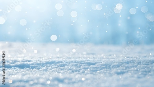 Soft snowfall sparkles gently in a serene winter landscape with blurred blue background.