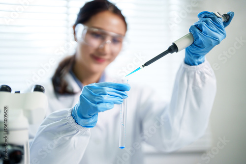 Asian adult woman scientist conducts laboratory research using pipette test tube developing new science medicine technology in sterile lab environment
