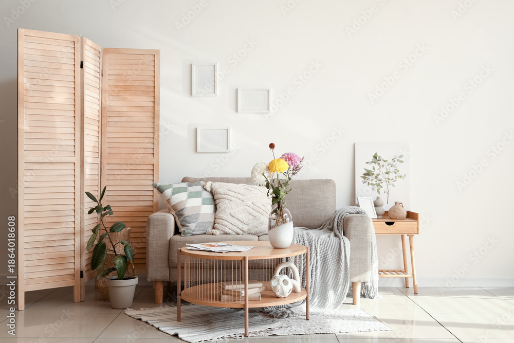Obraz premium Interior of living room with sofa, folding screen and ikebana on table