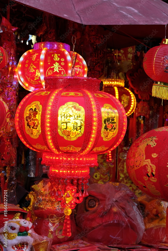 Fototapeta premium Vibrant red Chinese lanterns with gold Chinese characters illuminate a festive market stall
