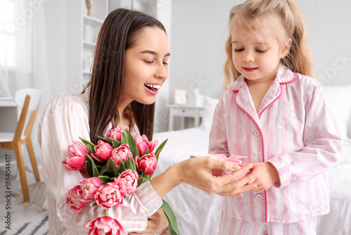 Little girl congratulating her happy mom with bouquet of beautiful flowers an...