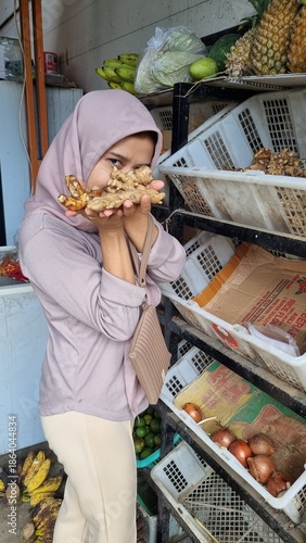 Woman in hijab shopping for fresh produce at a vibrant market stall.