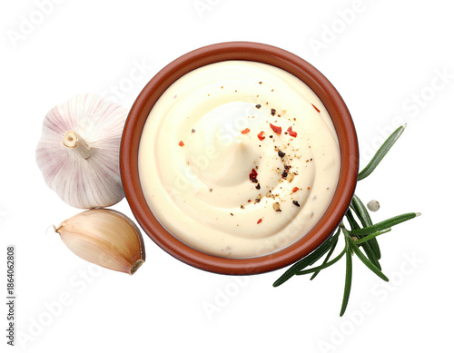Overhead shot of creamy sauce in a bowl, surrounded by garlic, peppercorns, and herbs
