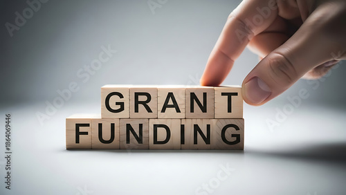 Hand arranging wooden blocks with grant funding text on them