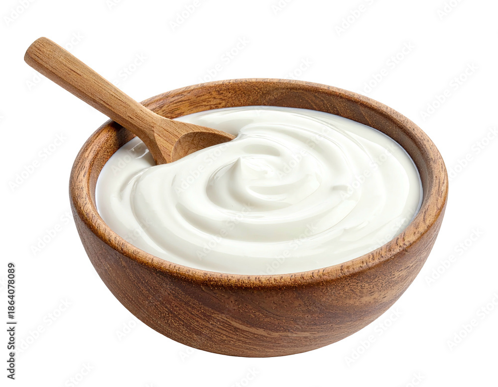 Fototapeta premium A wooden bowl filled with creamy, white dairy product, and a wooden spoon resting inside