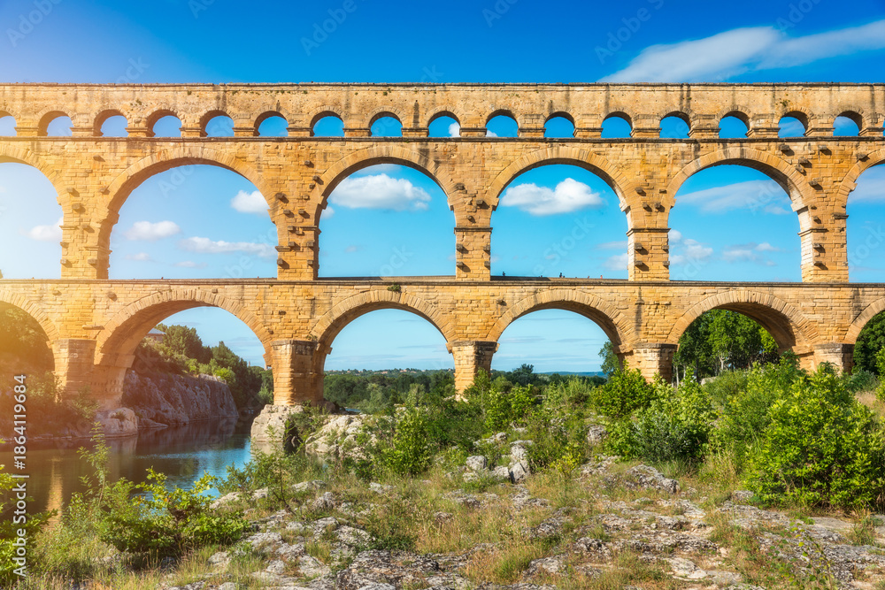 Fototapeta premium Exploring the majestic Pont du Gard aqueduct in France, discover the stunning architecture of the ancient Pont du Gard aqueduct in southern France. River Gard, Languedoc-Roussillon, France.