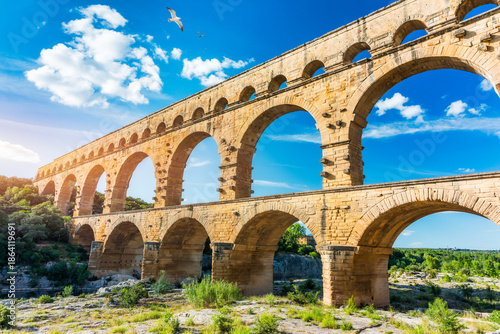 Exploring the majestic Pont du Gard aqueduct in France, discover the stunning architecture of the ancient Pont du Gard aqueduct in southern France. River Gard, Languedoc-Roussillon, France. © daliu