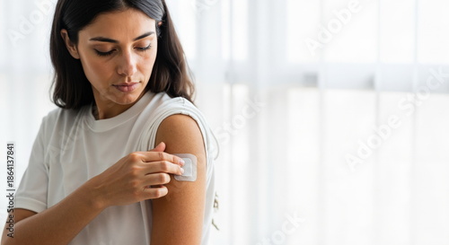 A young woman applies a transdermal medical patch to her upper arm. Healthcare, self-care, and modern treatment concept. Copy space for text Free Download A young woman applies a transdermal medical patch to her upper arm. Healthcare, self-care, and modern treatment concept. Copy space for text - GFXLoad