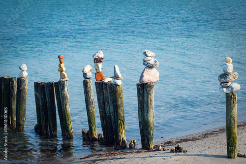 Several colorful stone towers on wooden stilts on the Baltic Sea beach.