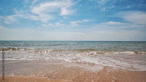 Vászonkép Gentle waves caressing sandy crimean shoreline, blue sky with scattered clouds,