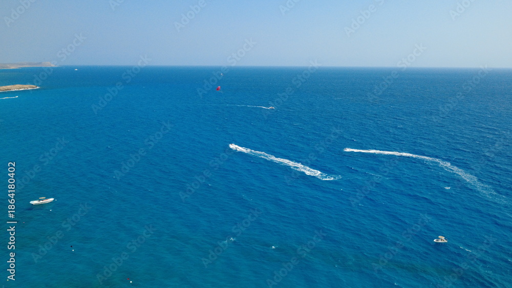 Obraz premium Aerial view of coastal town and rocky shoreline with calm sea at sunset