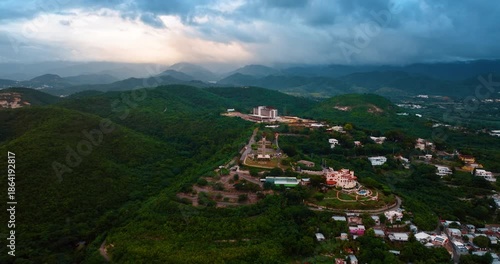 Flying closer to the Watchman Cross on the verdant mountain hill. Landmark of Ponce, Puerto Rico. Dramatic dark clouds over the rocks at backdrop.