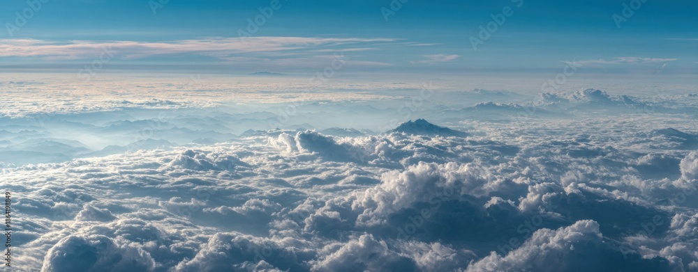 Naklejka premium High-altitude view of vast, fluffy clouds, with hints of mountains