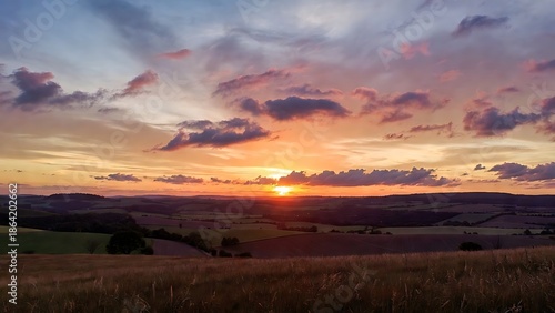 Wallpaper Mural Vibrant sunset over rolling rural hills with a radiant sky and scattered clouds at dusk Torontodigital.ca