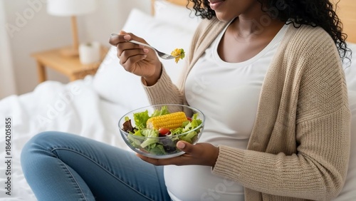 Pregnant woman eating healthy salad at home.