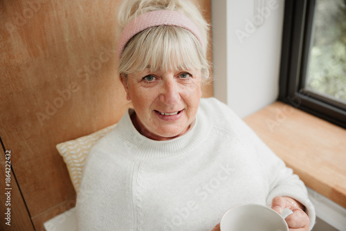 Tableau sur toile Warm portrait of a senior woman with blonde hair and pink headband, smiling kind