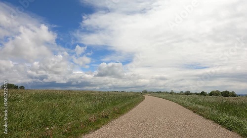 Beautiful aerial footage capturing a road connecting to a horizontal sky with soft clouds, paired with gentle glass pieces or objects blowing across the ground.