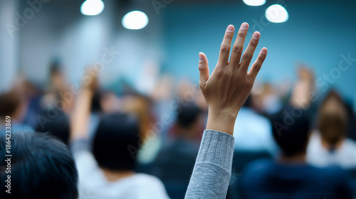 Audience members raising hands during a conference or seminar, representing participation and engagement.
