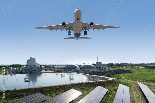 An airplane flies over a biogas plant. A symbol of decarbonization and carbon neutrality in transport. © scharfsinn86