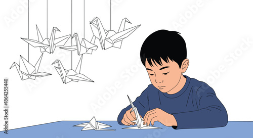 A focused young boy sits at a table carefully folding a paper crane with several completed origami birds hanging above him.