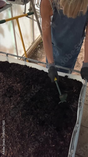 Female gardener cultivating soil with a hoe