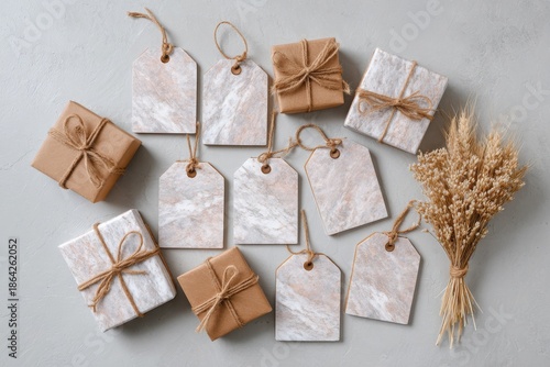 Collection of beautifully wrapped gifts and blank gift tags with dried wheat stalks on a light textured background