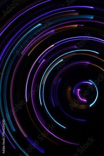 A long exposure photograph. Light painting photography; vibrant multicolour fairy lights in a circle swirl pattern against a black background