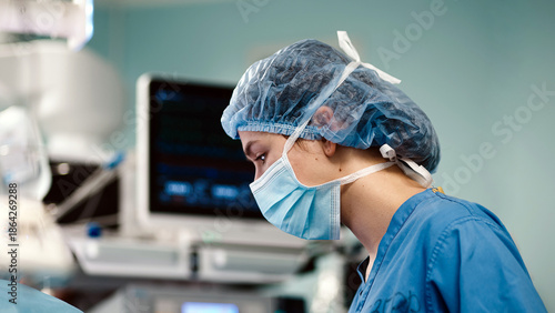 Konstfotografi Female surgeon in blue scrubs and surgical mask, focused on procedure in operati