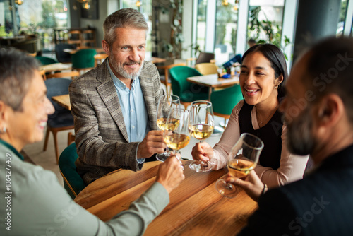 Foto Adult and mature friends smiling and toasting wine in a restaurant