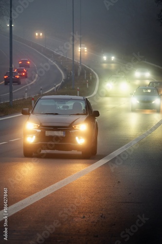 Bright headlights of a car driving on foggy winter road