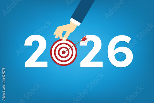 Human hand holding business target for a business year 2026. Red arrow hits target center. Business success concept.	