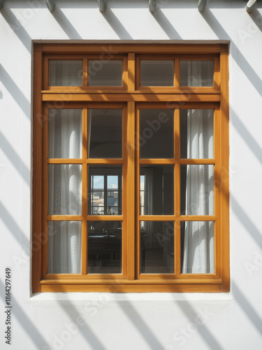 Wooden window with white curtains in warm sunlight with striped shadows on white wall for home decor