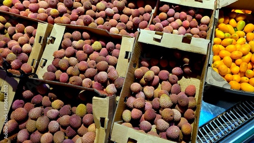 Fresh Lychee and Kumquat Fruits Displayed in Boxes at a Market During Daylight Hours