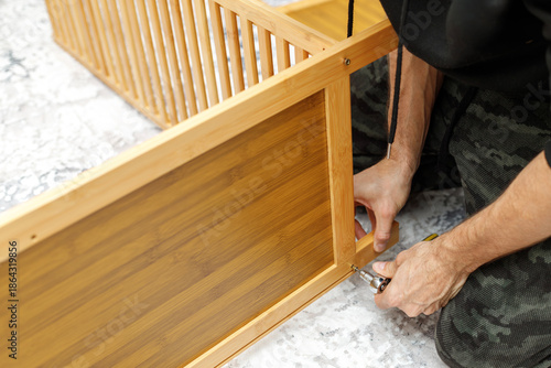 Close-up of male hands assembling wooden furniture using hand tools