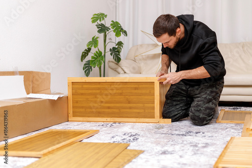 Young man assembling furniture in  living room. Concept of home improvement,