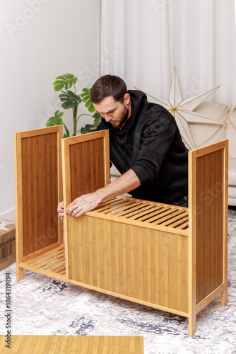 Young man assembling furniture in  living room. Concept of home improvement,