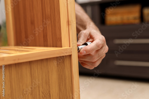 Close-up of male hands assembling wooden furniture using hand tools