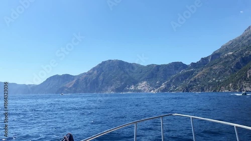 Luxury yacht sailing along the Amalfi coastline exploring famous cities Positano and Amalfi, view from the front deck on amazing seascape and mountain hills along the seashore, summer vacation on boat