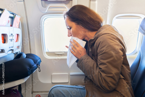 Quadro su tela Adult caucasian woman feeling sick inside airplane cabin holding paper bag